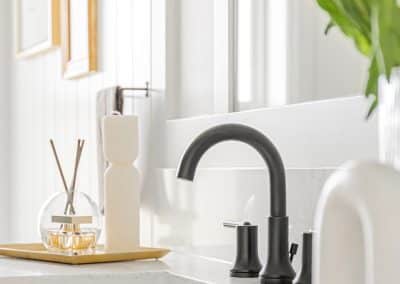 An image of a bathroom with a black faucet and a plant made by custom home builder langley in Langley, BC