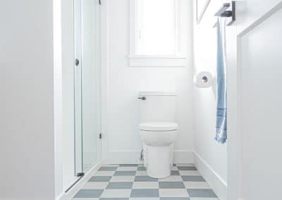 An image of a bathroom with black and white tiles with toilet and shower that is made by home renovation contractors in Langley, BC