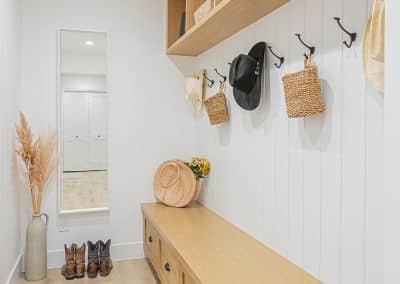 A hallway with custom designed wooden shelves and hats on hook with custom additions in Langley, BC