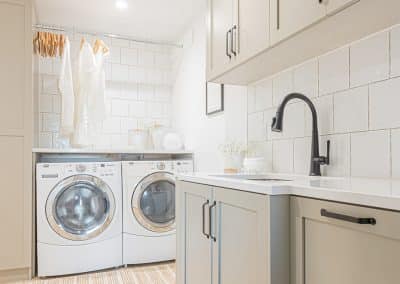 A picture of a laundry area with washing machines, cabinet and a sink made by a custom home builder langley in Langley, BC