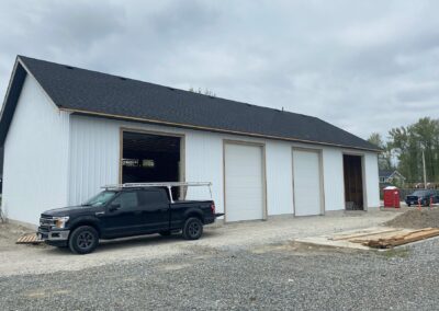 A white pole barn with a black roof, a testament to expert pole barn construction in Langley, BC