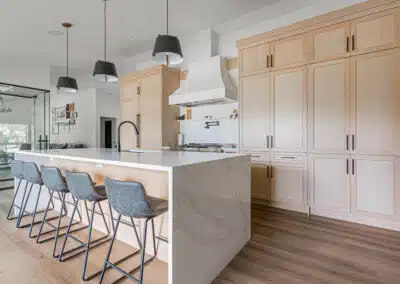 Spacious kitchen with light wood cabinets, a large island, and pendant lights by home renovation contractors in Langley.