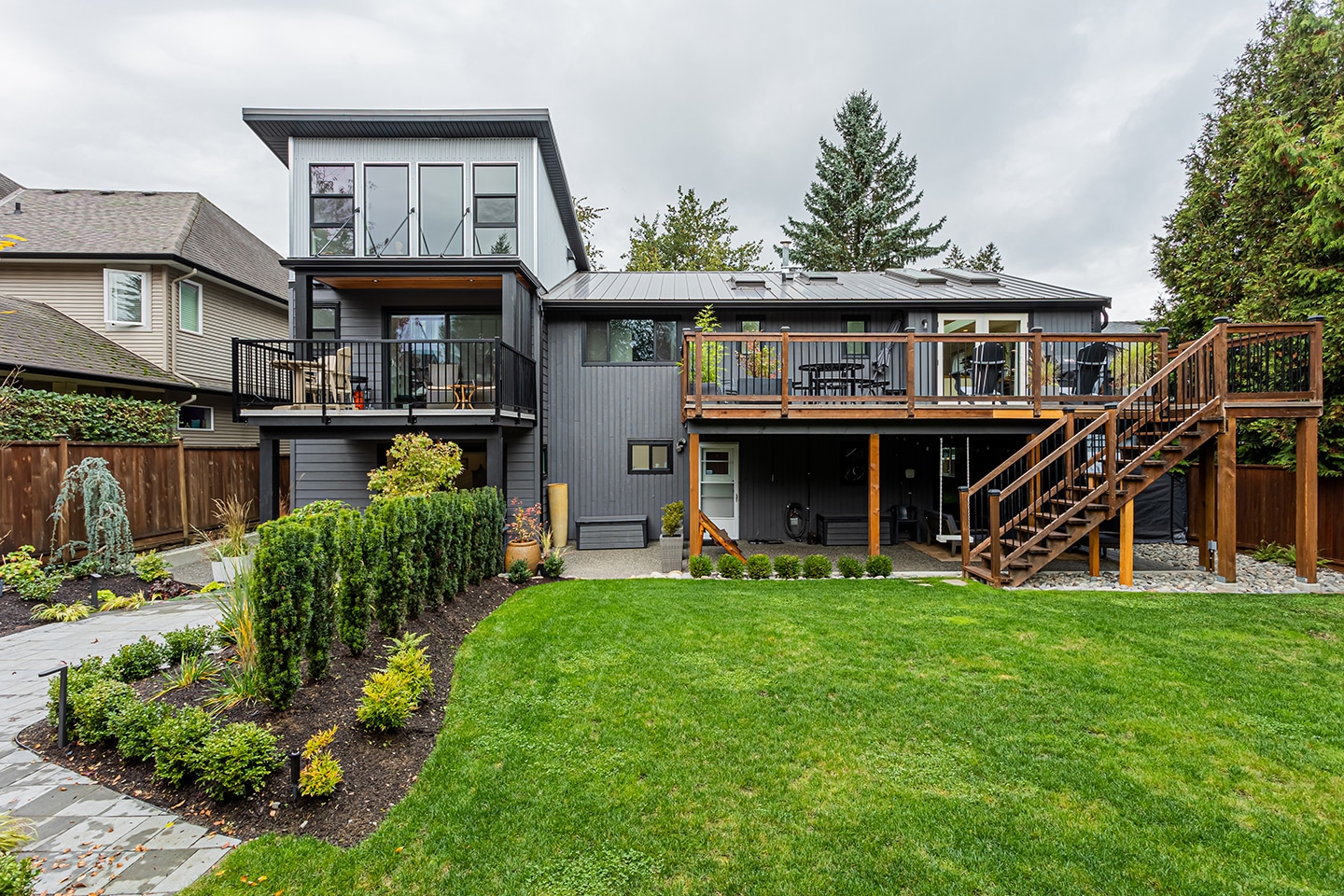 A grey siding and grey roof with a large wooden deck by Bowline Construction, home renovation contractors in Langley