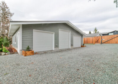 A large, detached outbuilding garage with three car bays and a gravel driveway made by by Bowline Construction in Langley, BC