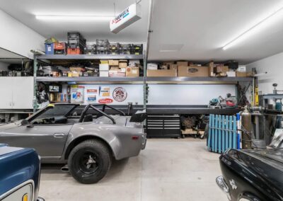 A well-equipped outbuilding garage with a classic car, shelves full of tools and supplies, and a workbench by Bowline Construction in Langley, BC