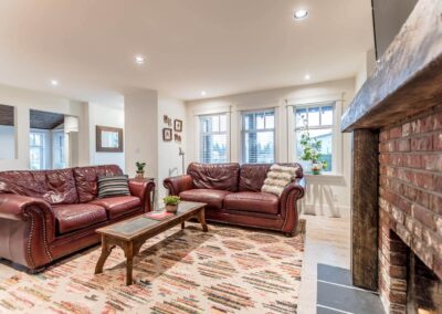 A living room with two red leather sofas, a wooden coffee table, a patterned rug, and a brick fireplace
