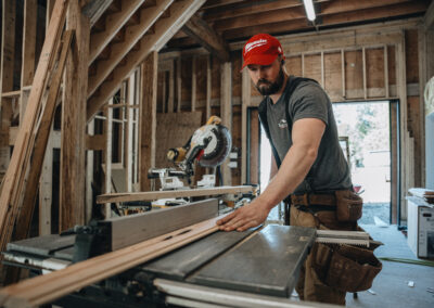 Bowline Construction team member holding a plank while using a measuring device for pole barn construction in Langley, BC