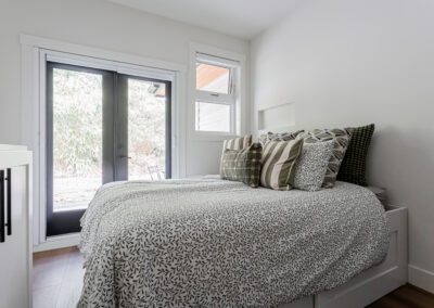 A bright, modern bedroom with white walls and light wood laminate flooring by a renovation company in Langley, BC