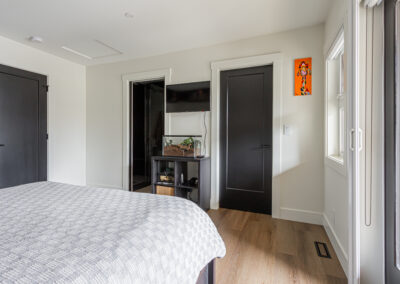 A bright, modern bedroom with white walls and light wood laminate flooring.