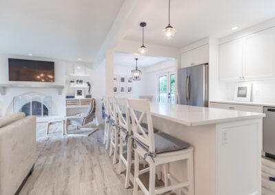 kitchen and living room with white cabinets, stainless steel appliances by kitchen renovation contractors in Langley, BC