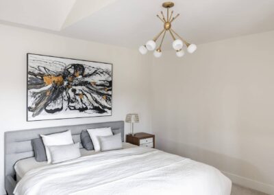 Bedroom with a gray upholstered bed, a large floral painting, and a modern chandelier in Langley, BC
