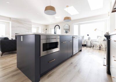Contemporary kitchen featuring a gray island with a white countertop, pendant lights, and stainless steel appliances in Langley, BC