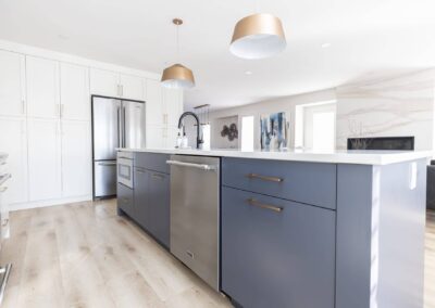 Contemporary kitchen featuring a gray island with a white countertop, pendant lights, and stainless steel appliances in Langley, BC