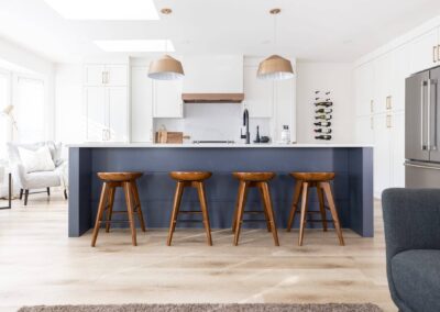 Kitchen island with four stools, pendant lights, and white cabinets by kitchen renovation contractor in Langley