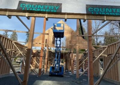 A pole barn under construction with a scissor lift in the center and the words "Country Timber" written across the top by Bowline Construction in Langley, BC.