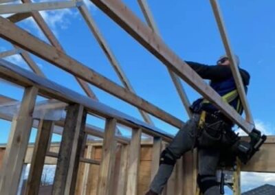 A pole barn construction worker on a wooden roof in Langley, BC