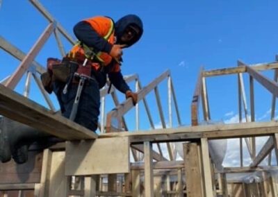 A enovation contractor on top of a wooden plank in a process of pole barn construction in Langley, BC