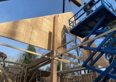 A pole barn under construction with a crane lifting a large piece of plywood into place by Bowline Construction in Langley, BC