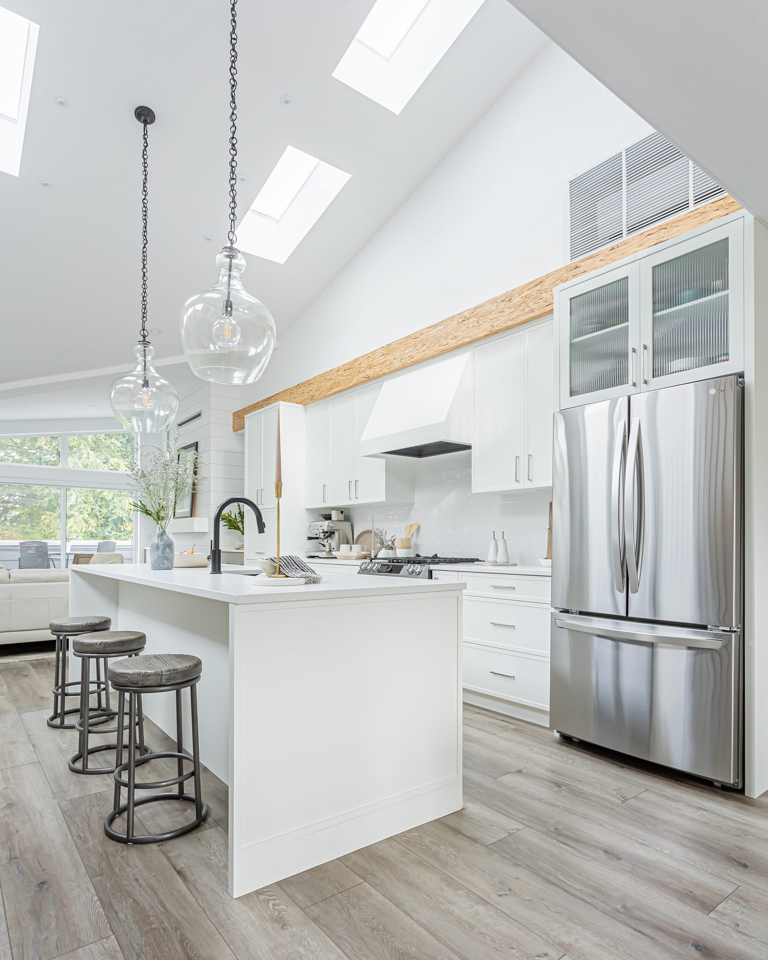Modern kitchen with white cabinets, a large island, and plenty of natural light by design-build contractors in Langley
