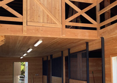 A large, empty barn with multiple stalls and a loft by pole barn construction contractors in rural British Columbia