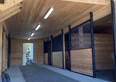 A large, empty barn with multiple stalls and a loft by pole barn construction contractors in Langley