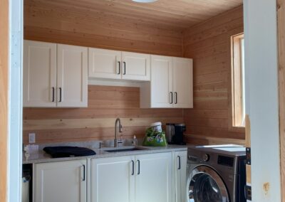 A bright and airy laundry room with white cabinets, a sink, and a washer and dryer by home renovation contractors in Langley, BC