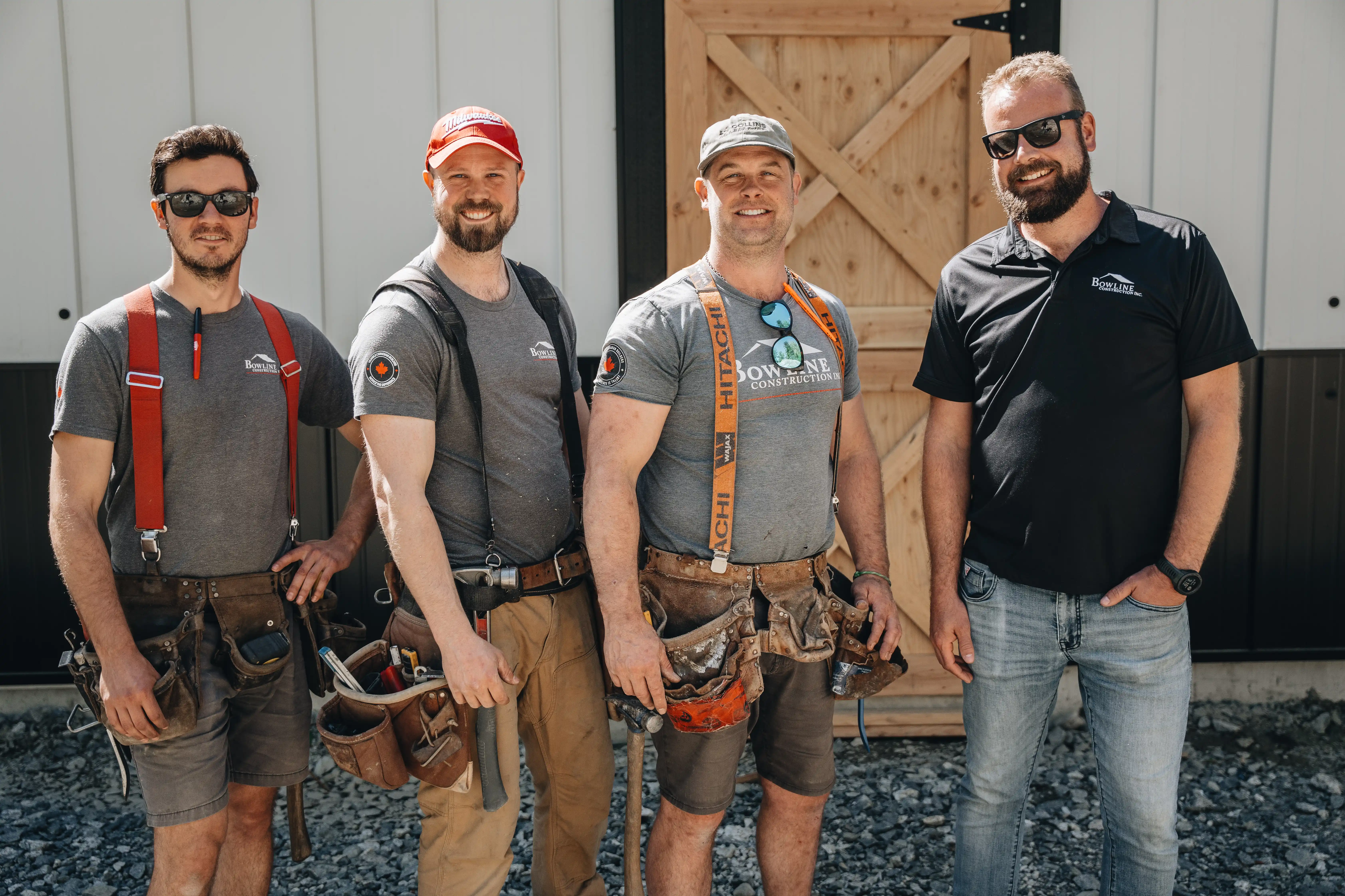 Four-person Bowline Construction team wearing branded shirts and tool belts posing outside a Langley, BC project