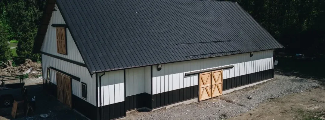 Modern equestrian facility design barn with black metal roof and wood doors by Bowline Construction in CA