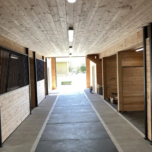 Wide barn aisle with proper lighting, stall access, and smooth flooring built for safe equestrian facility design by Bowline Construction in CA