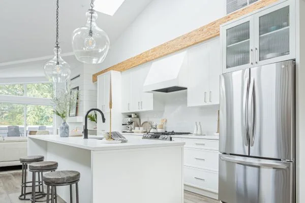 Modern kitchen renovation with white cabinetry, wood accent beam, and stainless steel appliances by Bowline Construction in White Rock, BC