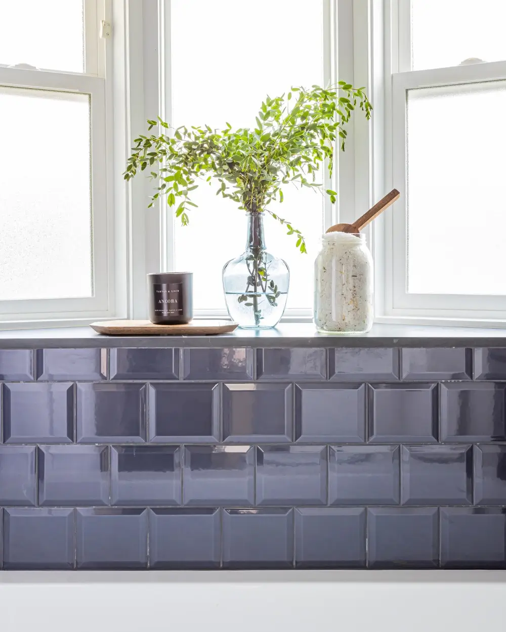 Elegant bathroom window design with navy tile backsplash and decorative accents for home renovations Surrey by Bowline Construction