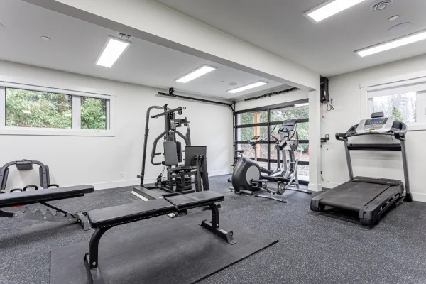 Modern home gym with fitness equipment and natural lighting by Bowline Construction in Maple Ridge, BC