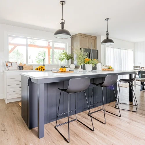 Stylish kitchen with dark island, wood flooring, and bright dining area by Bowline Construction in Langley, BC