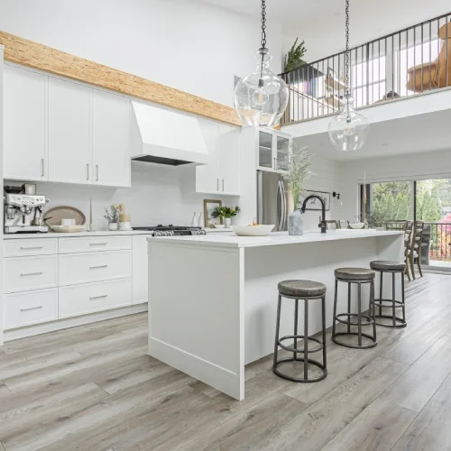 Modern open-concept white kitchen with large island and pendant lighting by Bowline Construction in Langley, BC